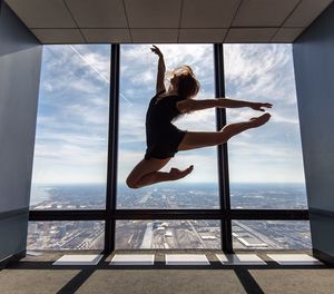 Full length of young woman jumping against clear sky