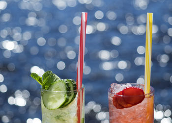 Close-up of lemonades in glasses against sea