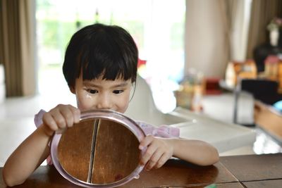 Portrait of asian girl holding mirror at home