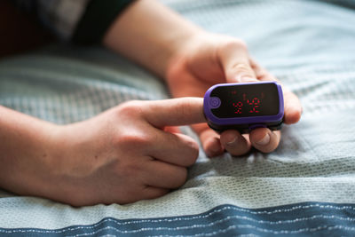 Close up of a person putting a pulse oximeter on their finger.