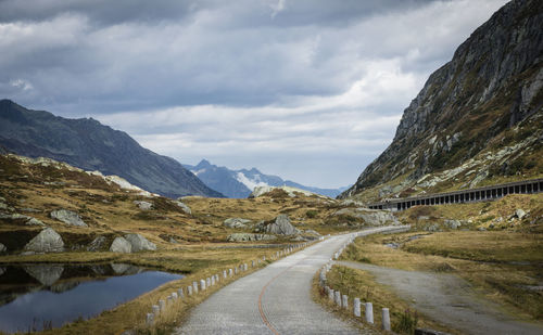 Empty road amidst mountains against sky