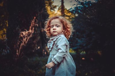 Portrait of cute girl standing on tree