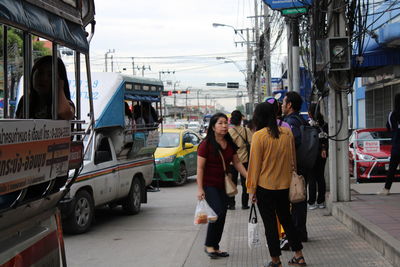 Rear view of people walking on road in city
