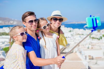 Family taking selfie through monopod against mykonos during summer