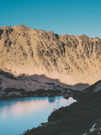 Scenic view of lake and mountains against clear blue sky