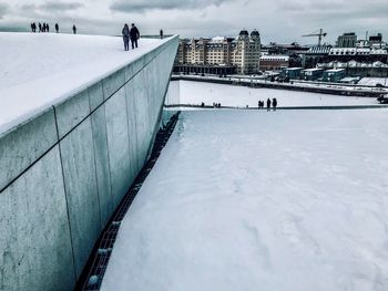 People on snow covered bridge against sky