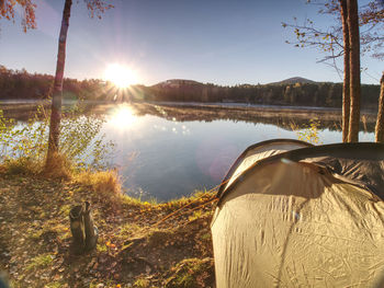 Tent on romantic place at lake shore. colorful fall forest. hilly horizon with last sun beams.