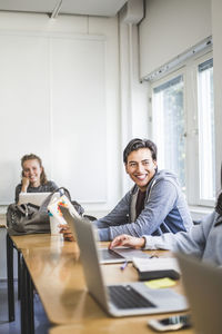 Smiling young man studying in university classroom