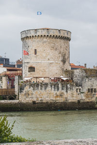 Old building by sea against sky