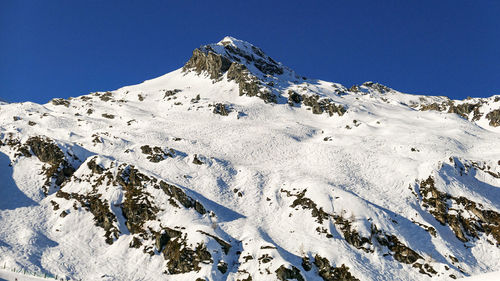 Snow sunny summit of rock alps in austria with skiing tracks in winter