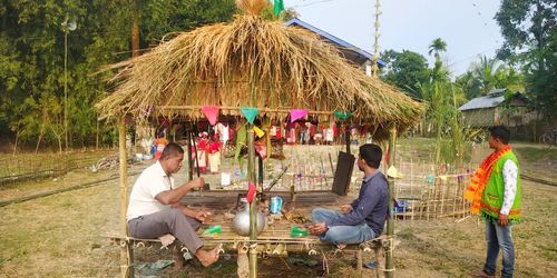 Group of people sitting on land against trees
