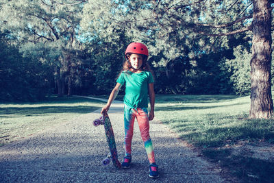 Full length portrait of boy standing by tree