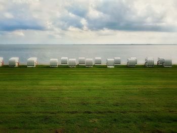 Scenic view of field by sea against sky