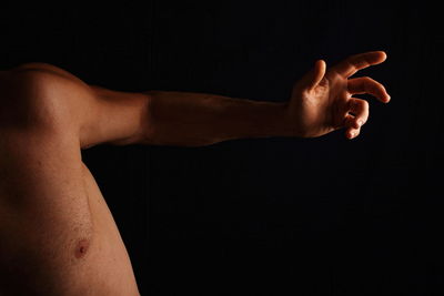 Close-up of shirtless man against black background