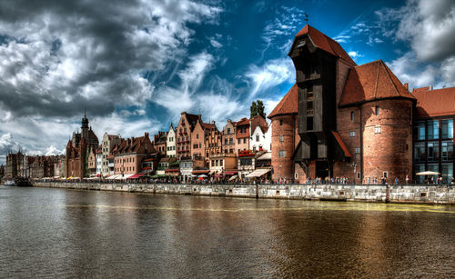 River by buildings against cloudy sky