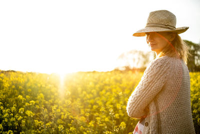 Portrait of a girl with a straw hat in a rapeseed field at sunset