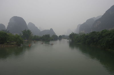 Scenic view of river by mountains against sky