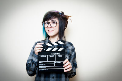 Portrait of smiling young woman standing against white background