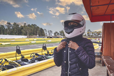 Portrait of adult woman holding helmet in go kart car.