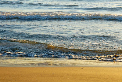 Waves rushing towards shore in a golden sea