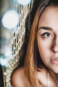 Portrait of beautiful woman standing by illuminated netting