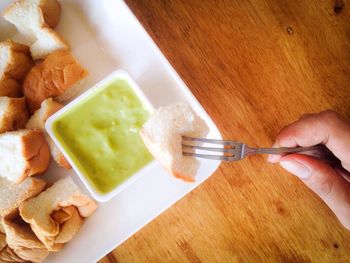 Cropped hand dipping bread in sauce