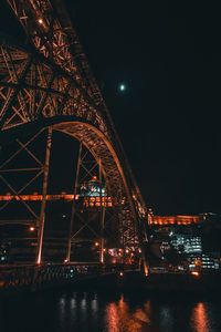 Low angle view of illuminated bridge over river at night