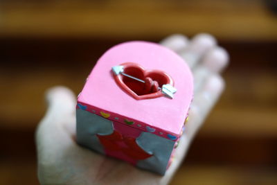 Cropped hand holding container with heart shape