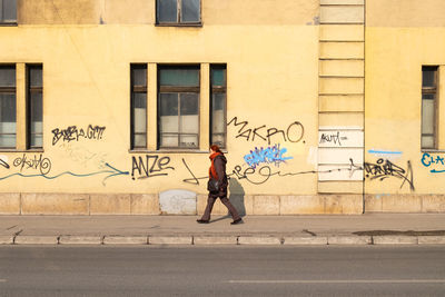 Full length of man walking on street by wall