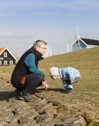 Side view of man an crouching by girl on field