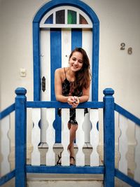 Portrait of smiling young woman standing outside house