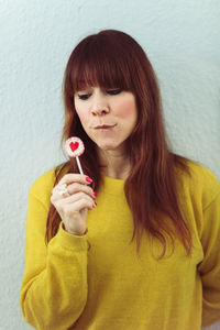 Portrait of beautiful young woman standing against wall