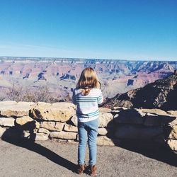 Full length rear view of girl by grand canyon national park against clear blue sky