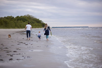 Family playing at beach against sky