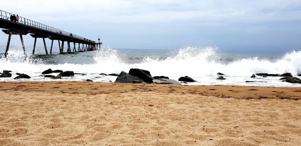 Scenic view of sea waves splashing on shore against sky