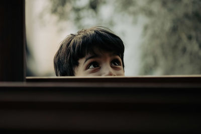 Side view of young boy looking through window
