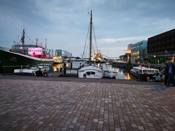 Sailboats moored on harbor in city against sky