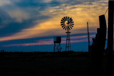 Low angle view of silhouette windmills on field against sky during sunset