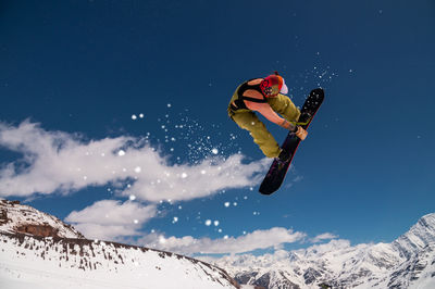 Low angle view of man skiing on snowcapped mountain against sky
