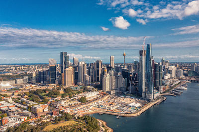 Aerial view modern skyscrapers and buildings against near ocean and cloudy sky. sydney, australia