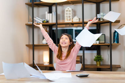 Portrait of young woman using mobile phone while standing in office