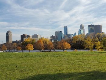 Park by buildings against sky during autumn