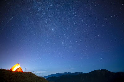 Low angle view of illuminated mountain against star field
