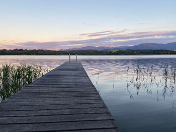 Pier over lake against sky during sunset