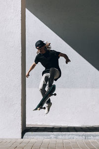 Man with skateboard jumping in front of wall