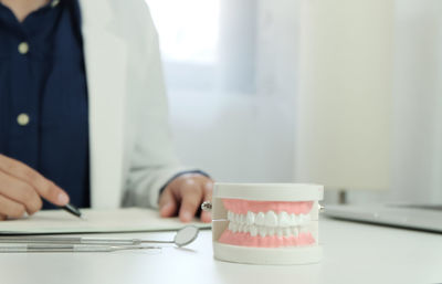 Midsection of dentist working with dentures in foreground at desk