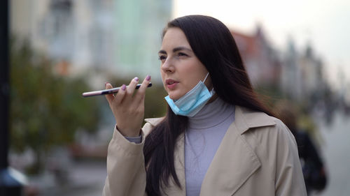 Portrait of young woman holding cigarette outdoors