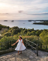 Young woman on a lookout terrace over sea. white dress, viewpoint, nature, sea, vacation.