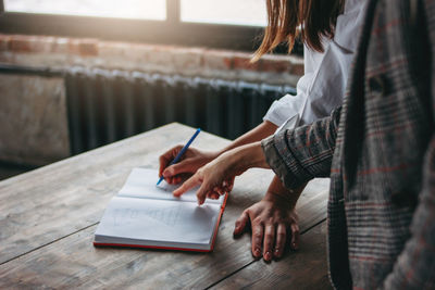 Midsection of woman reading book on table