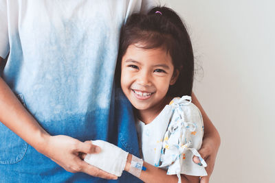 Girl embracing mother against wall in hospital